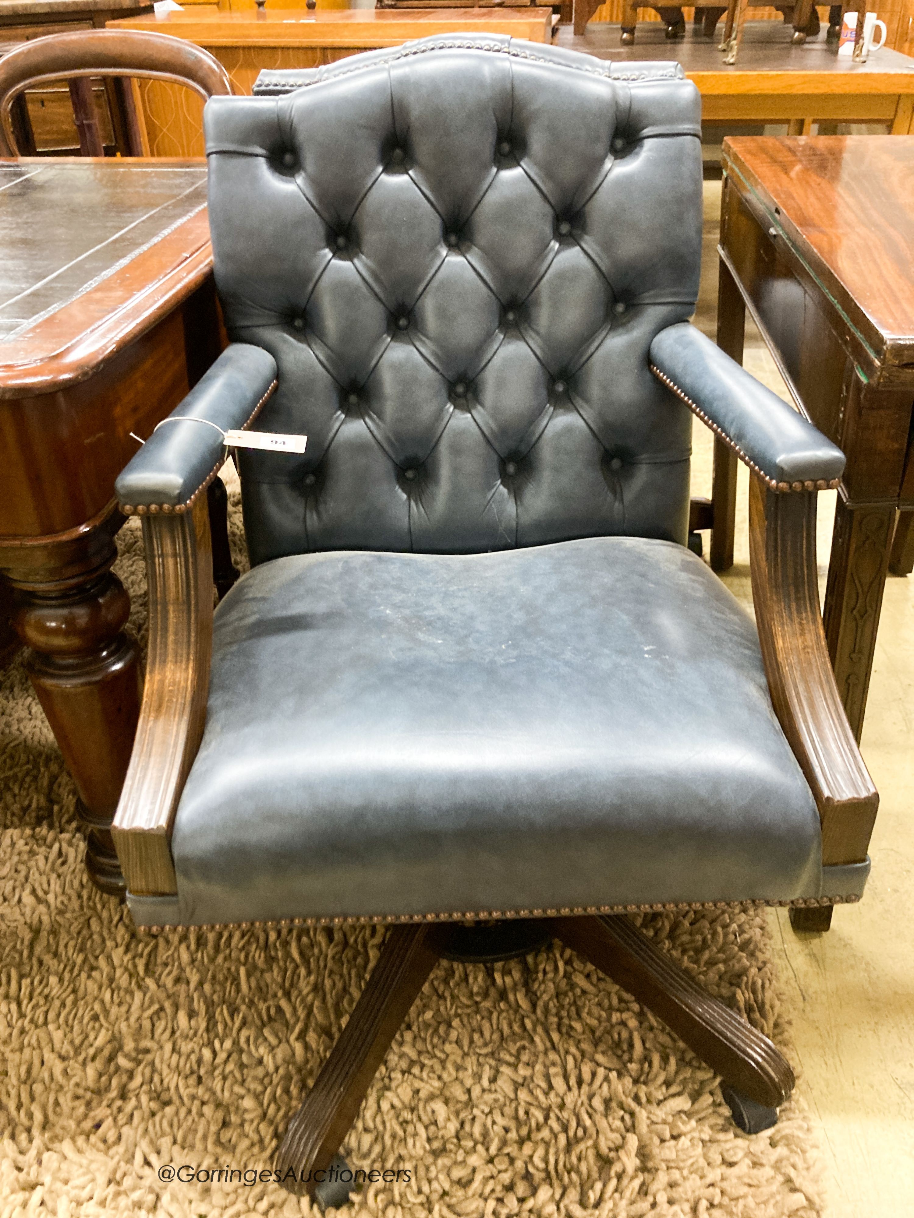 A pair of reproduction beech buttoned blue leather swivel desk chairs, width 60cm, depth 55cm, height 90cm